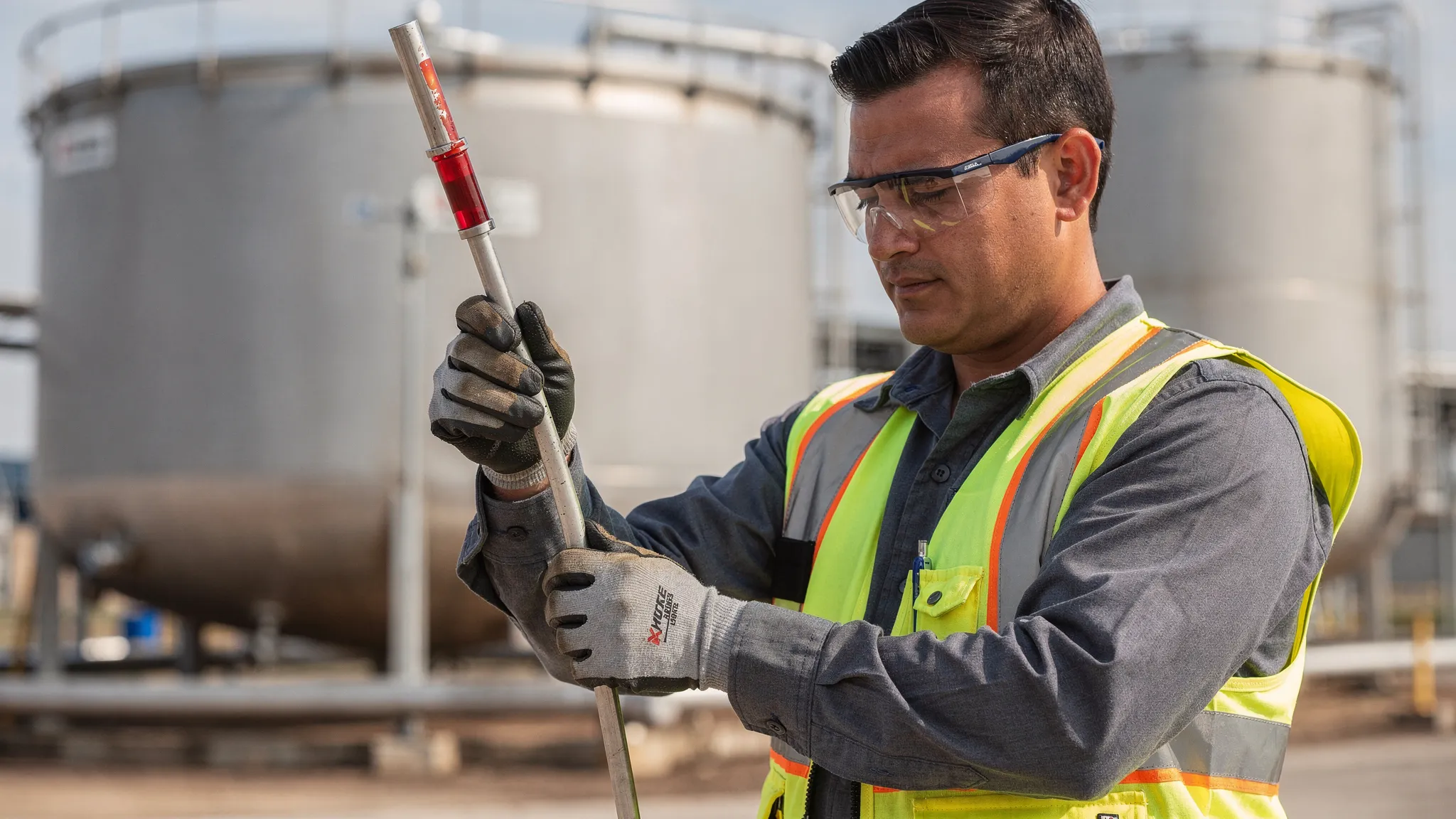 Fuel inspector checking a fuel tank dipstick with visible red dye