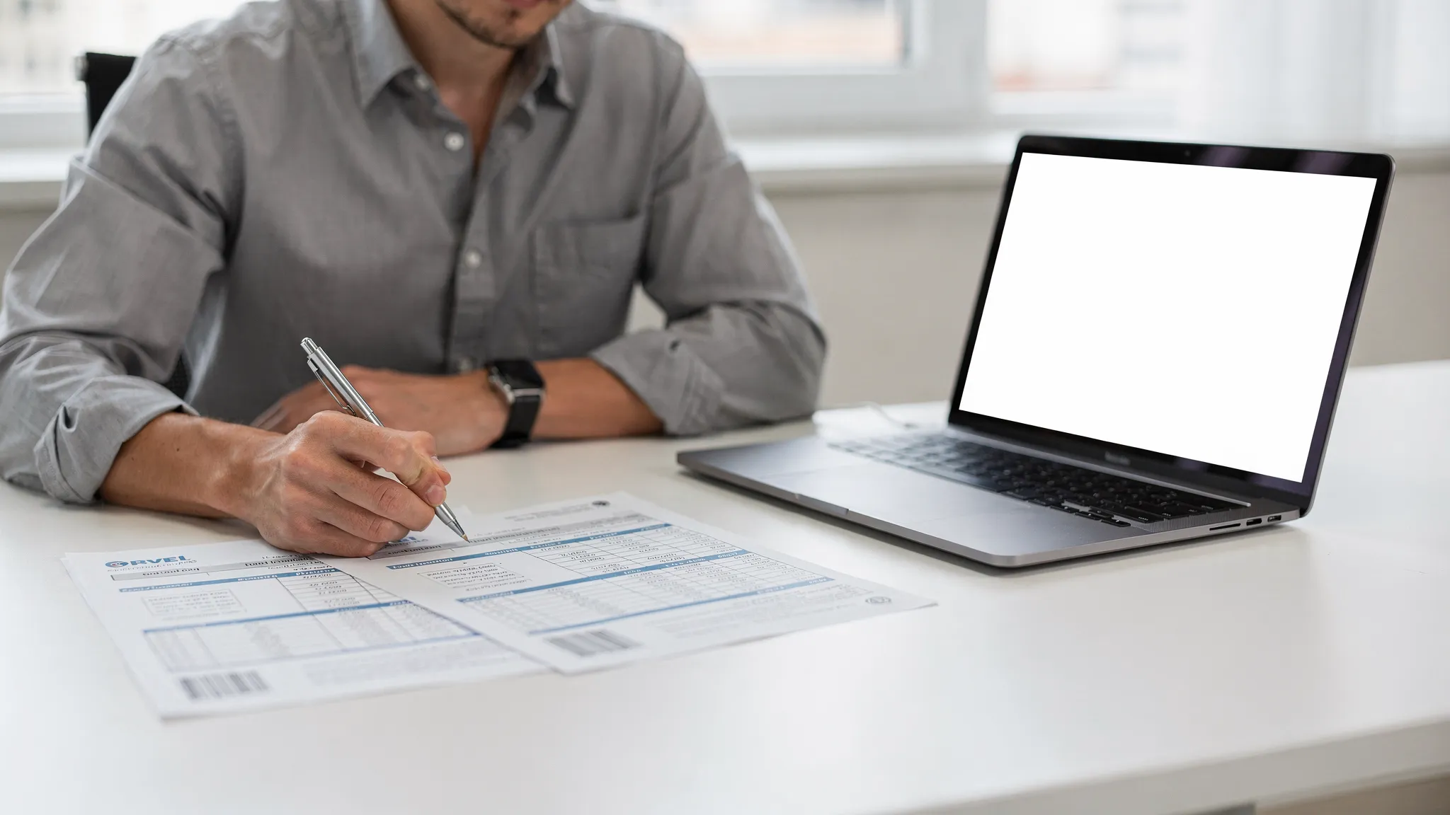 Person reviewing fuel transaction reports on paper next to a laptop with the screen facing forward and blank.